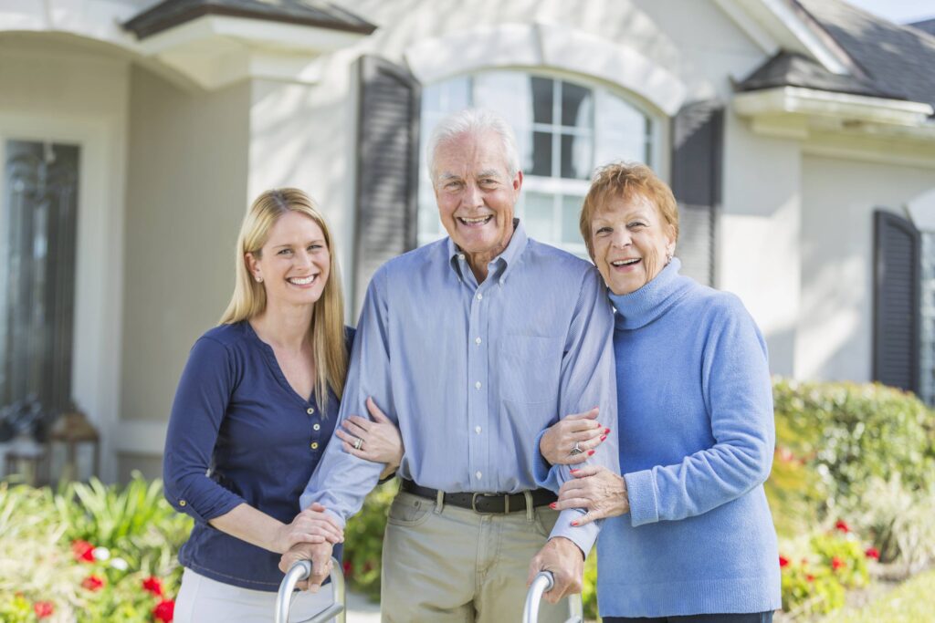 Woman-with-elderly-parents-standing-in-front-of-house-520325328_5760x3840